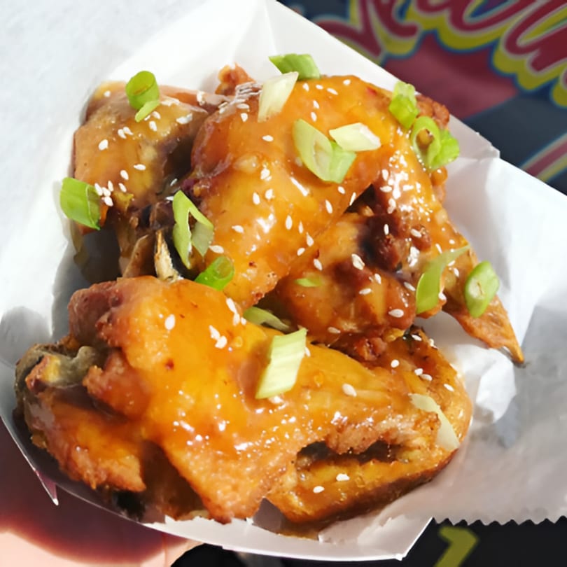 Sweet and savory Chick Wings and Things wings, garnished with sesame seeds and green onions.