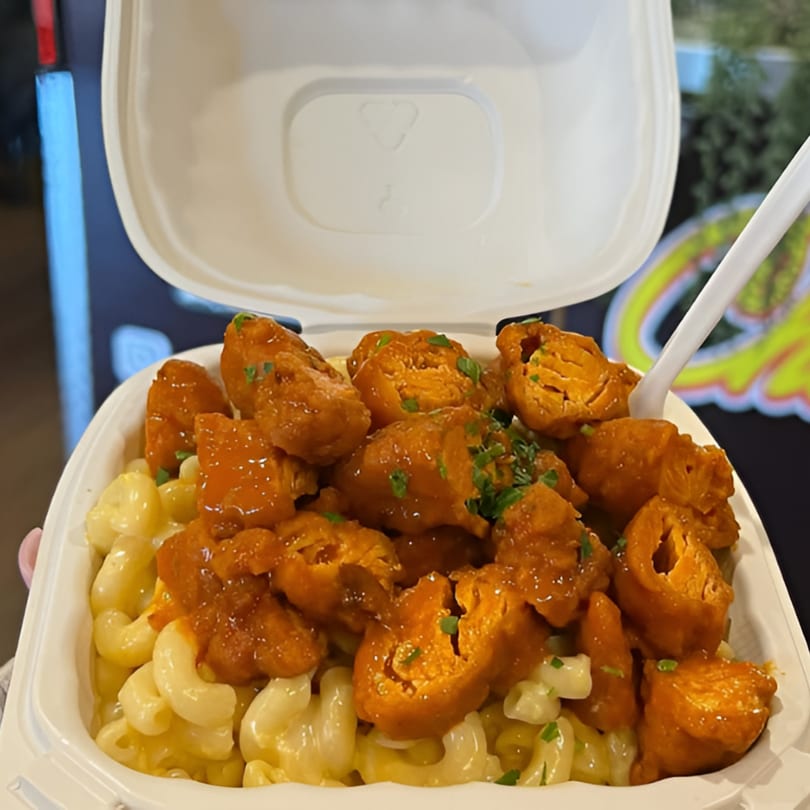 Chick Wings and Things mac and cheese topped with orange sauced wings and green garnish.